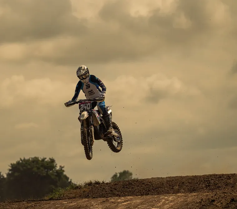 Motociclista de motocross saltando sobre un montículo