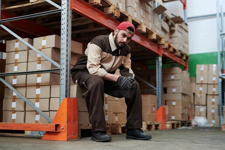 Trabajador sentado y cansado en una bodega de almacenamiento