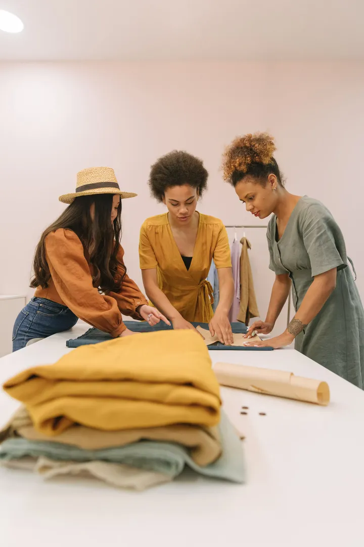 Tres personas trabajando juntas sobre una mesa de corte de telas