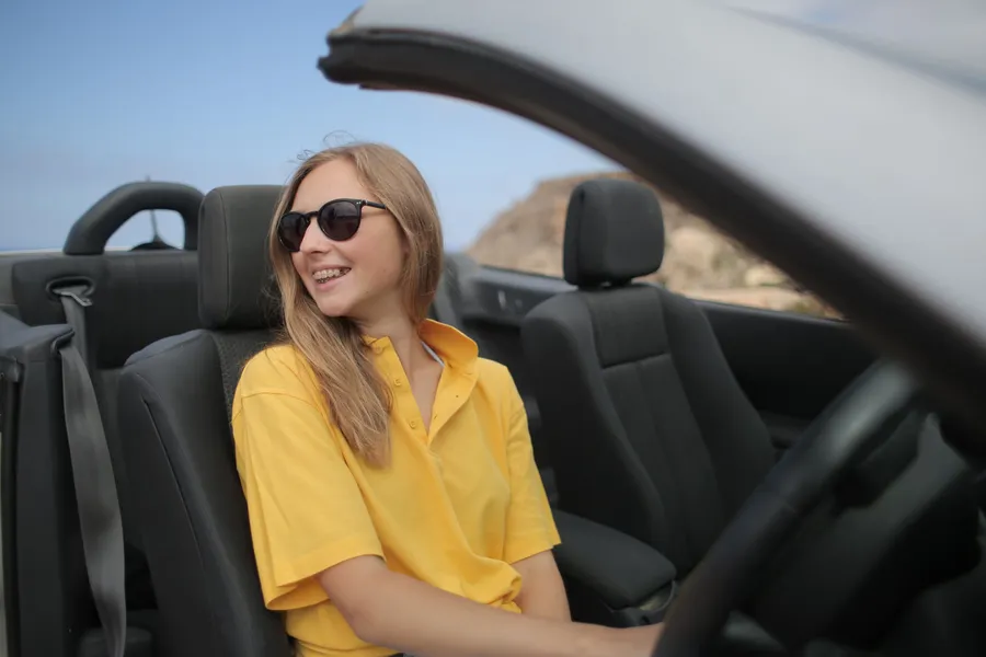Mujer sonriendo al volante de un carro convertible