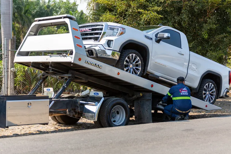 Grúa cargando una camioneta blanca en la vía