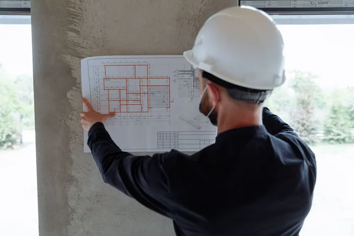 Ingeniero con casco revisando planos de un edificio