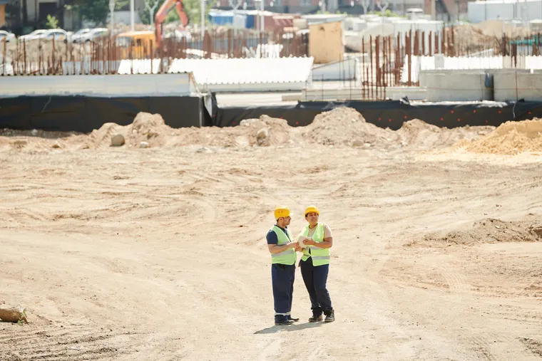 Dos trabajadores con casco y chaleco revisando una tableta en una obra
