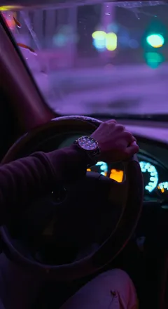 Manos al volante de un carro de noche
