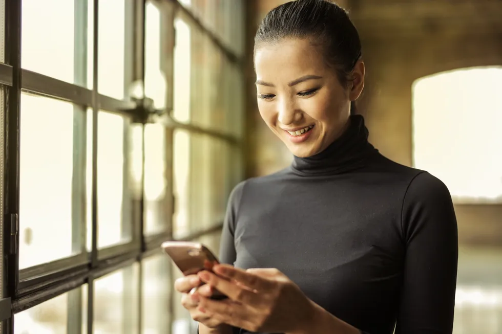Mujer sonriendo mientras cotiza su seguro desde el celular