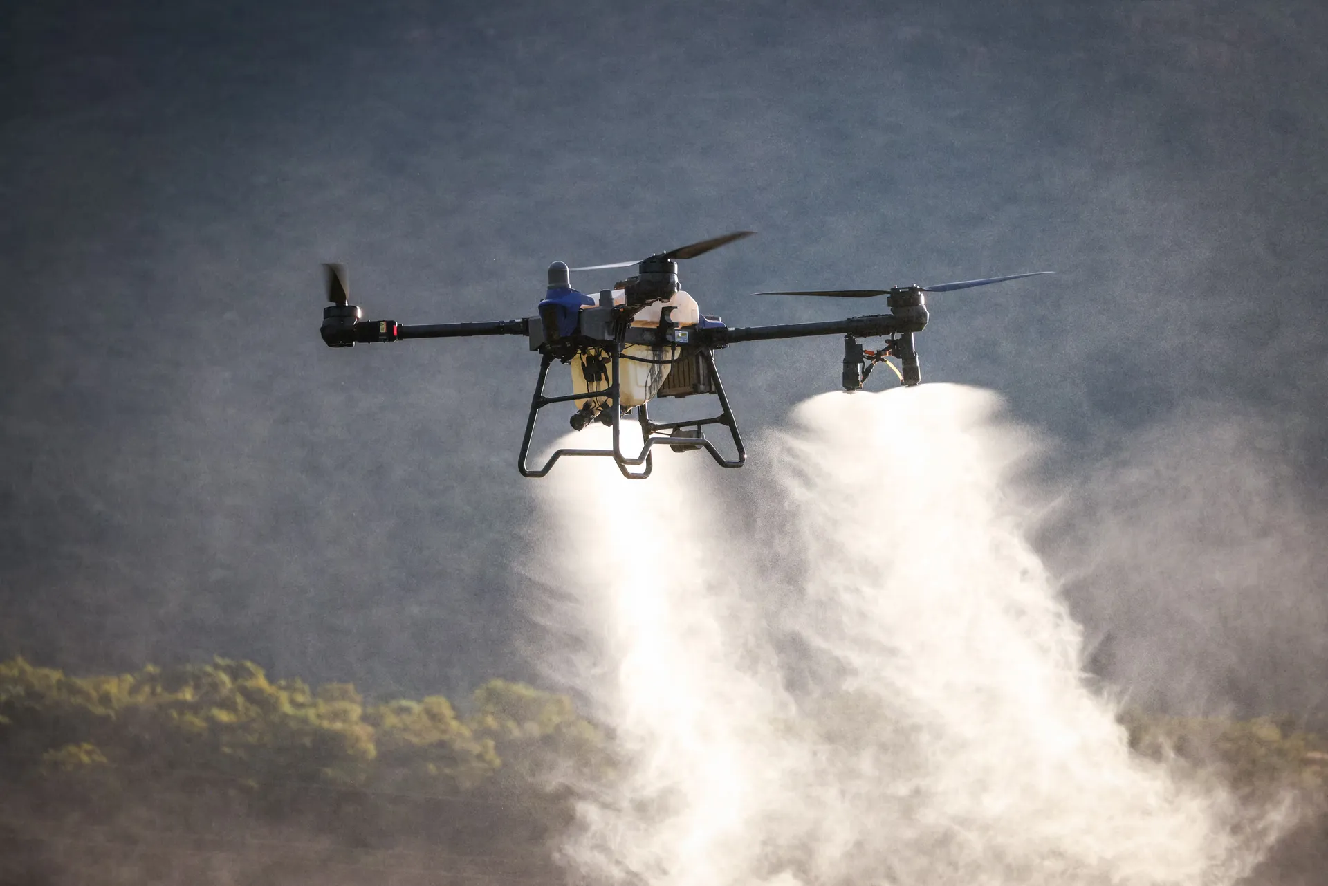 Dron profesional en vuelo, fumigando sobre un cultivo