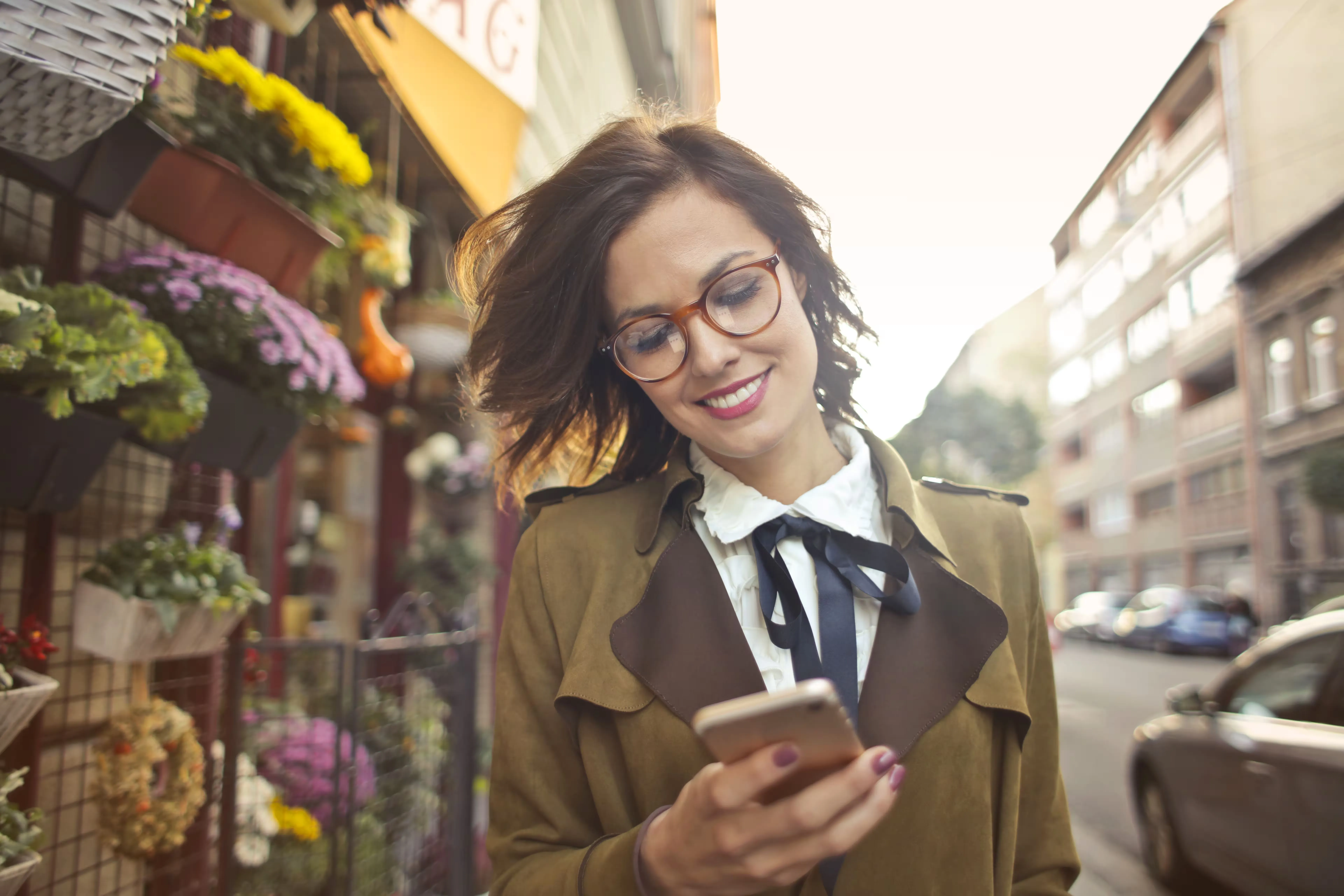 Una emprendedora revisa su celular frente a una floristería