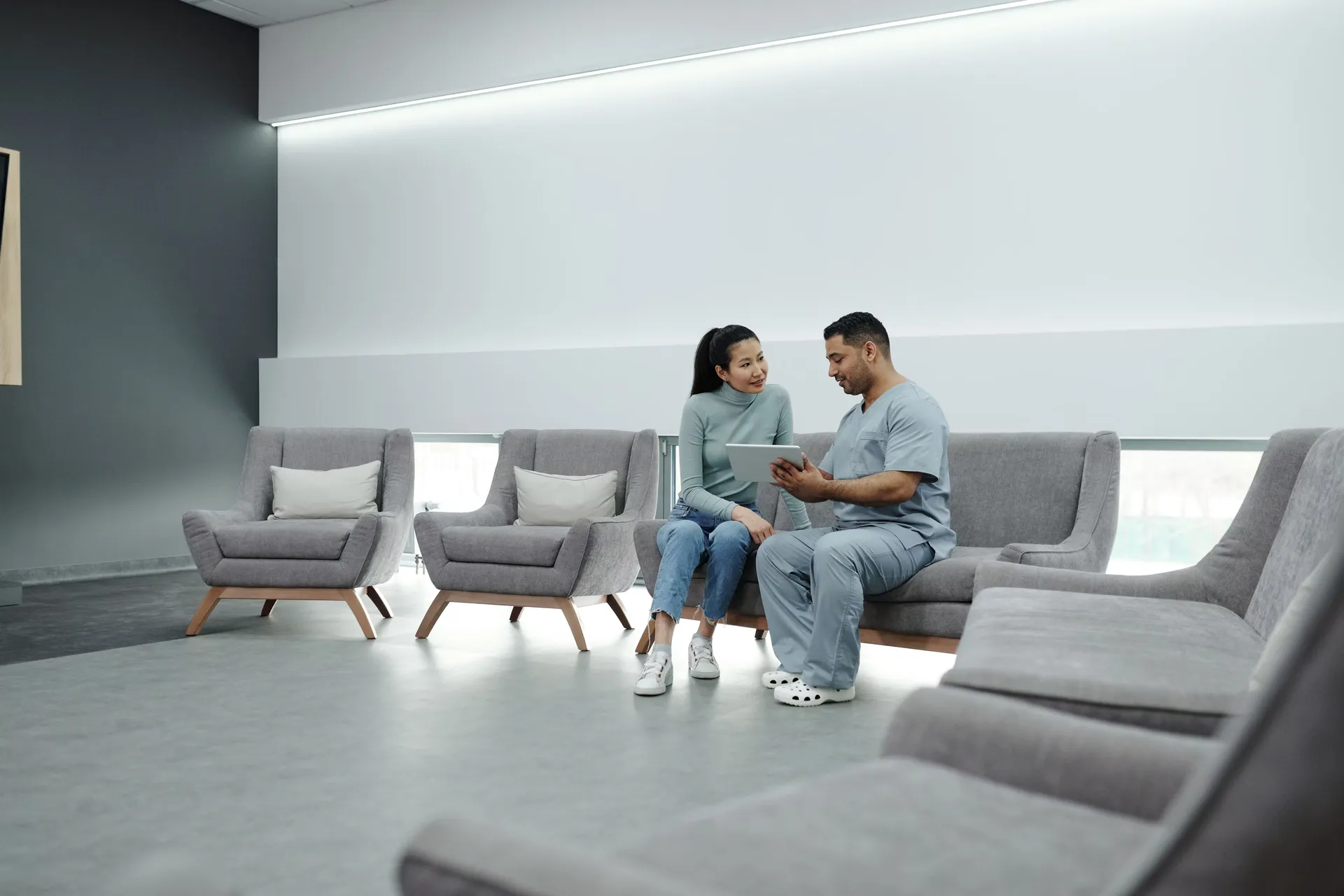 Pareja conversando con una tableta en la sala de espera de una clínica