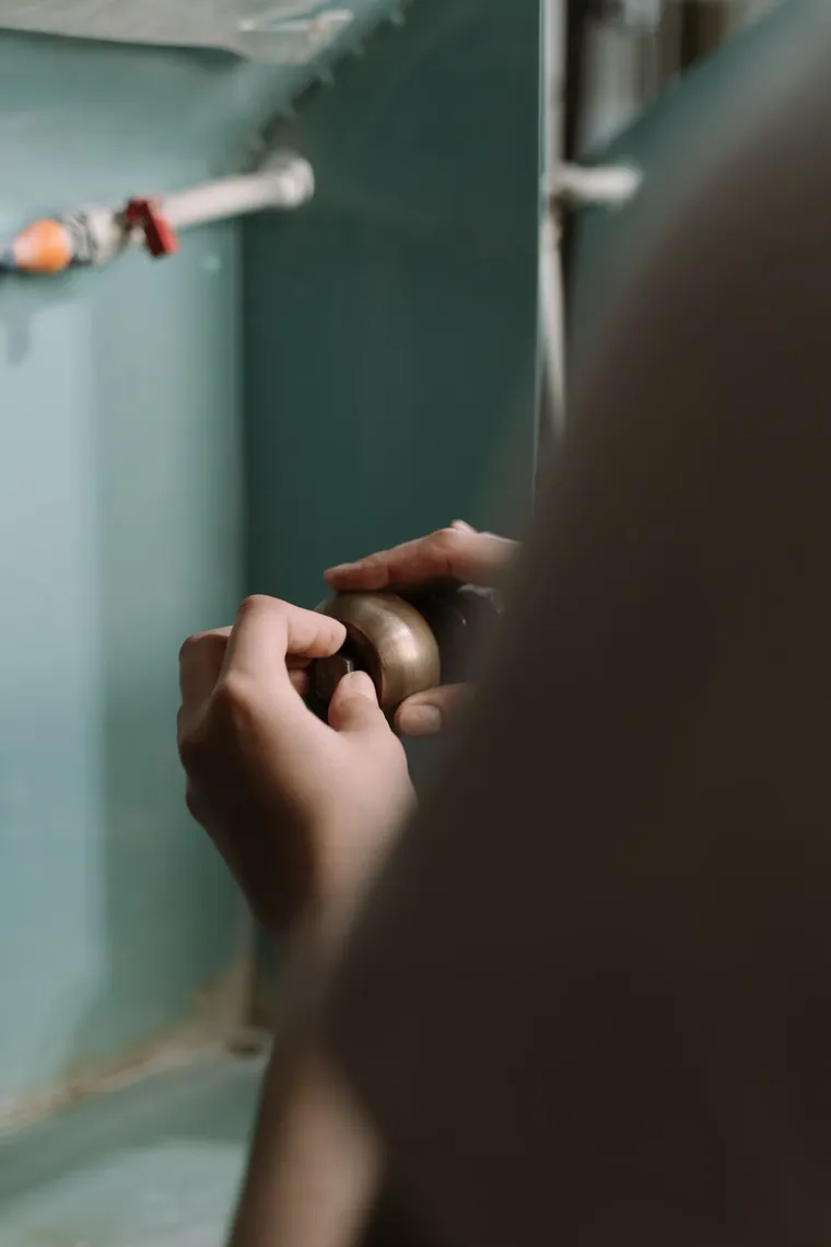 Manos reparando la tubería de una pared