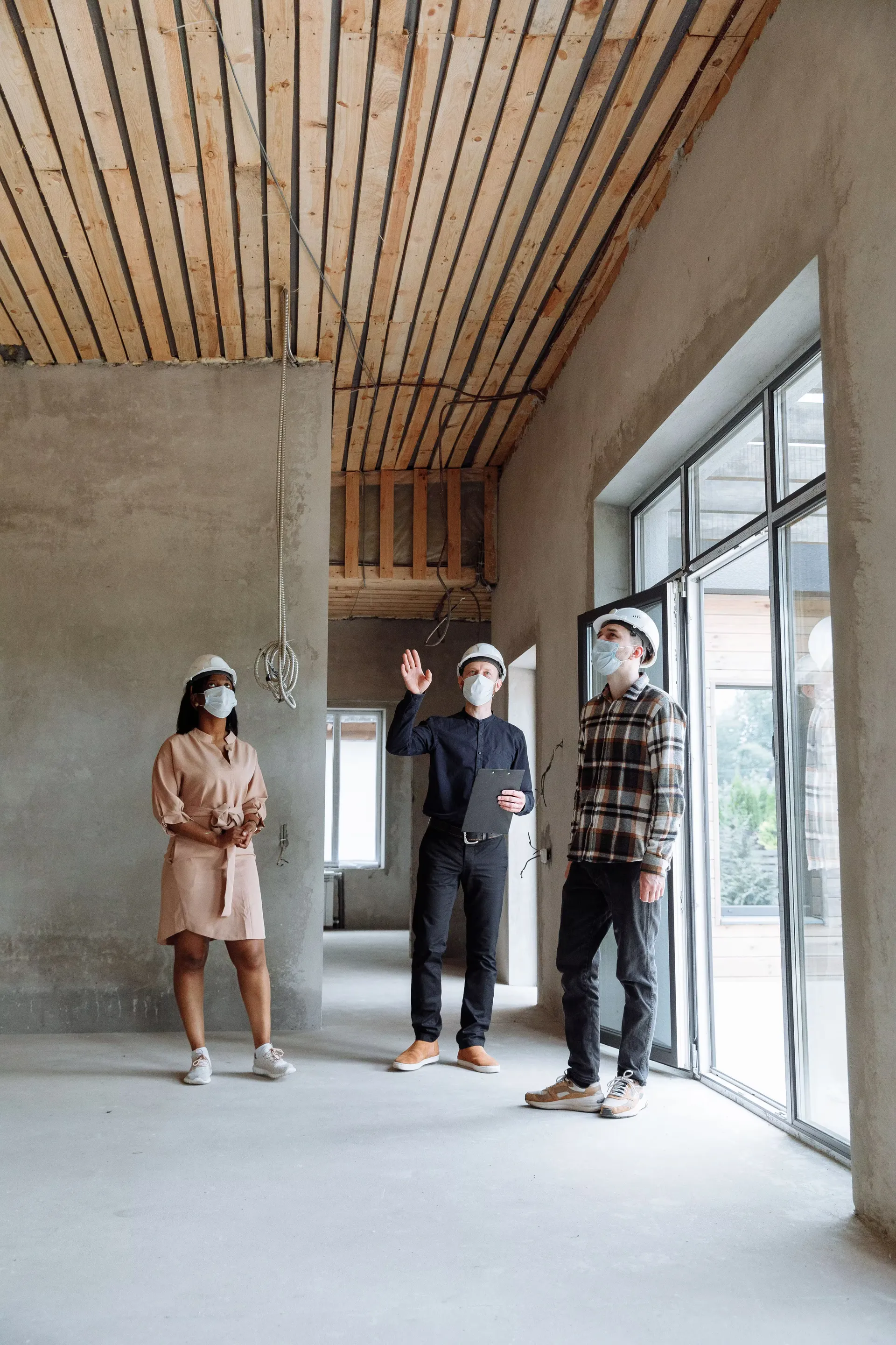 Equipo con cascos y tapabocas revisando una obra en construcción