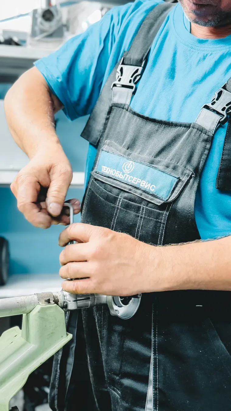 Técnico en overol reparando una máquina con sus herramientas