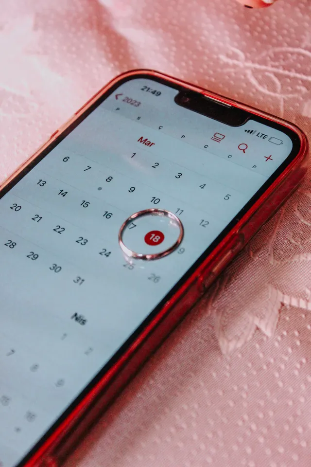 Mano sosteniendo un celular con un calendario y una fecha marcada