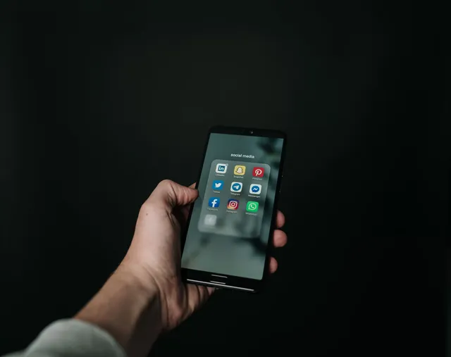 Mano sosteniendo un celular con las aplicaciones de mensajería en pantalla