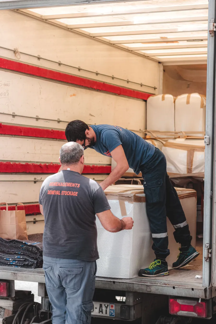 Dos operarios acomodando carga dentro de un camión