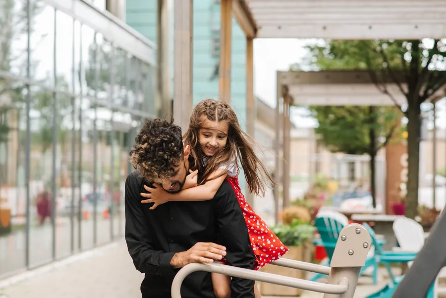 Padre cargando a su hija en la calle