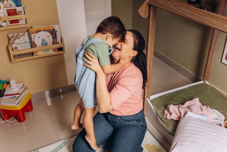 Madre abrazando a su hijo pequeño en la puerta de casa